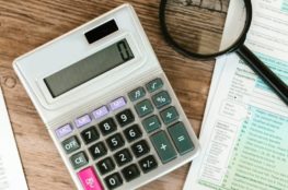 gray calculator and black magnifying glass on brown wooden surface