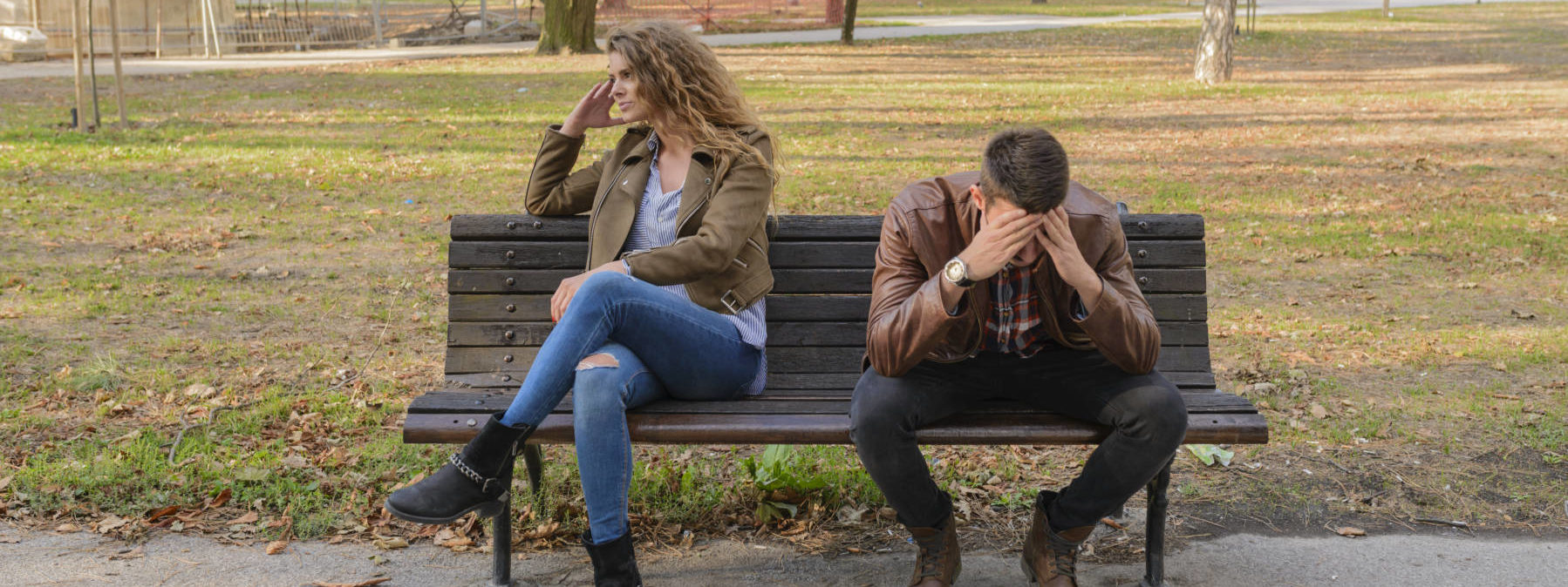 Woman and man sitting on brown wooden bench