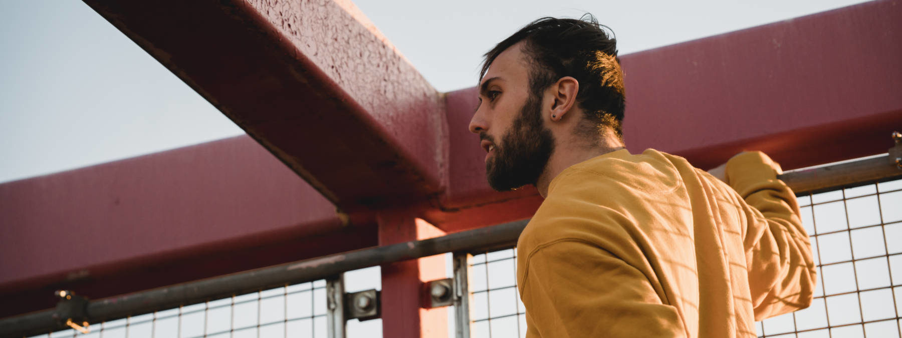 Hipster man near grid fence on bridge